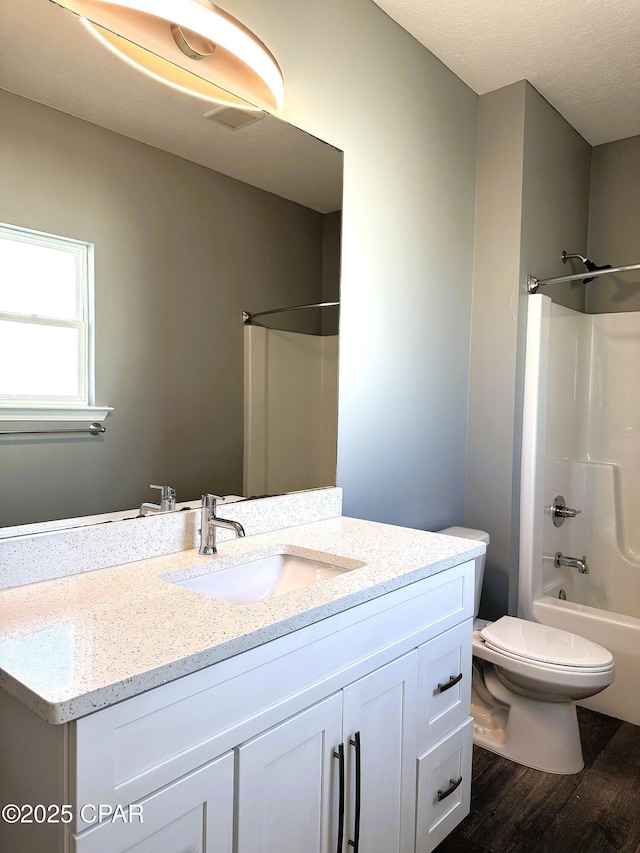 full bathroom featuring wood-type flooring, shower / bathing tub combination, vanity, and toilet