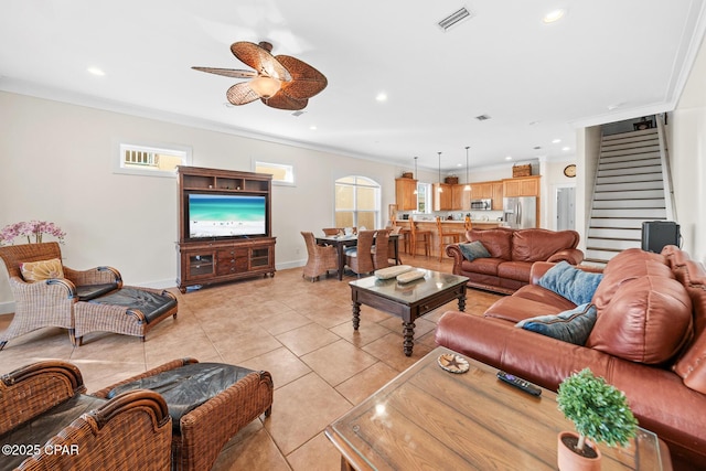 living room with light tile patterned flooring, a healthy amount of sunlight, ceiling fan, and ornamental molding