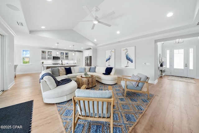 living room featuring ornamental molding, lofted ceiling, sink, and light wood-type flooring