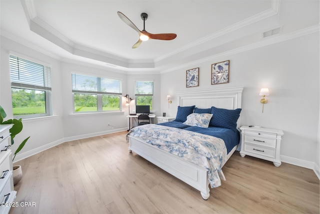 bedroom with multiple windows, light hardwood / wood-style floors, a raised ceiling, and ceiling fan