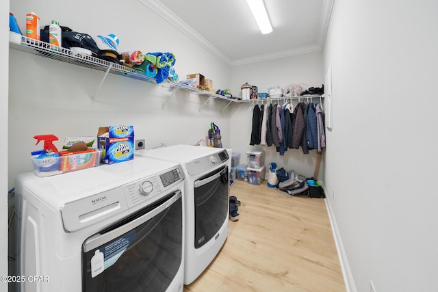 laundry room featuring washing machine and clothes dryer, ornamental molding, and hardwood / wood-style floors