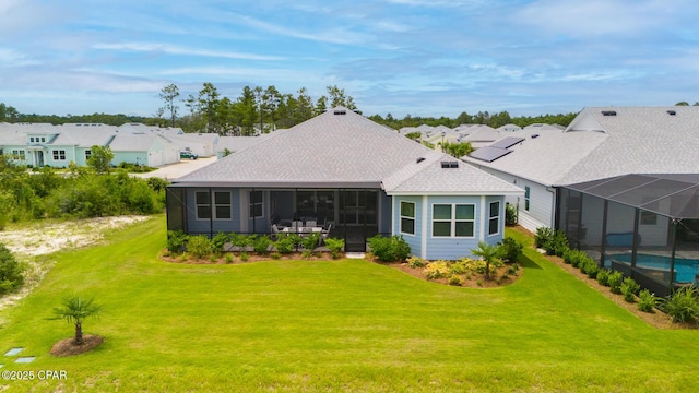 rear view of house featuring a yard and glass enclosure