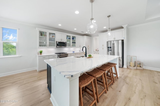 kitchen featuring white cabinetry, stainless steel appliances, a kitchen island with sink, and sink