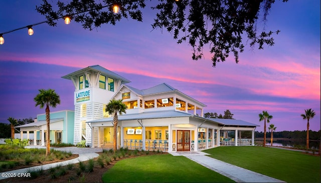 back house at dusk with a yard and french doors