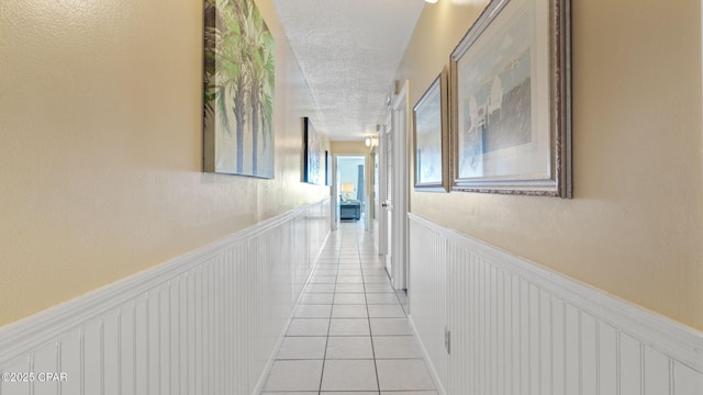 hall with light tile patterned floors and a textured ceiling