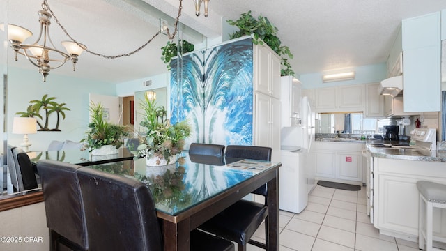 dining space featuring light tile patterned floors, a notable chandelier, and a textured ceiling