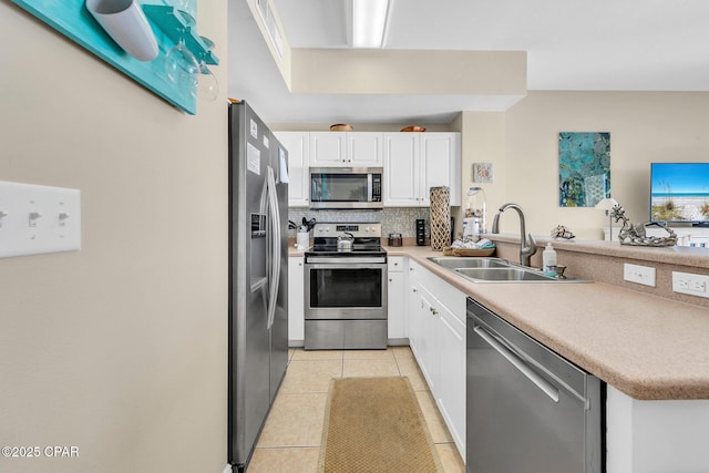 kitchen featuring sink, white cabinetry, light tile patterned flooring, decorative backsplash, and stainless steel appliances