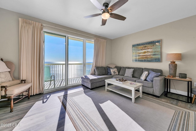 living room with hardwood / wood-style flooring, a water view, and ceiling fan