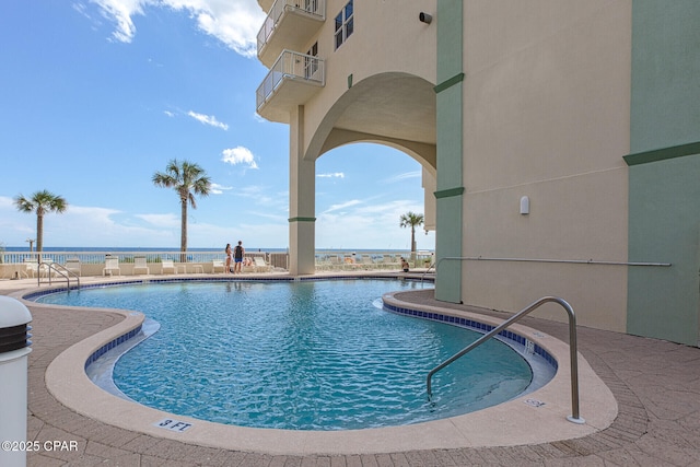 view of pool featuring a patio and a water view