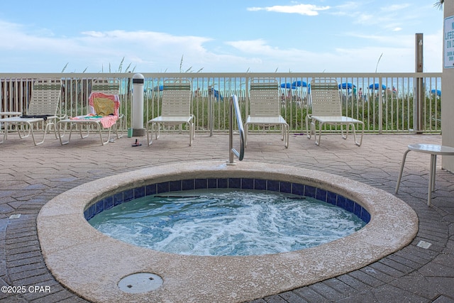 view of swimming pool featuring a patio, a water view, and a hot tub