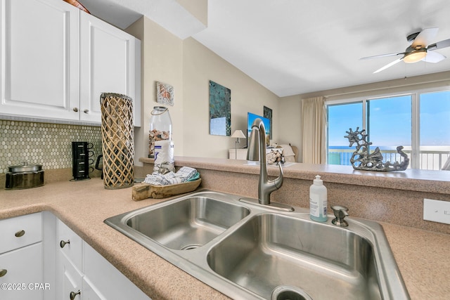 kitchen with sink, ceiling fan, white cabinets, and decorative backsplash