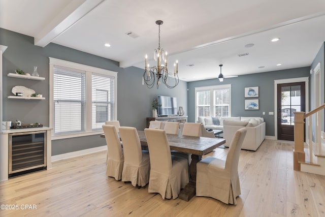 dining room with beam ceiling, plenty of natural light, beverage cooler, and light wood-type flooring