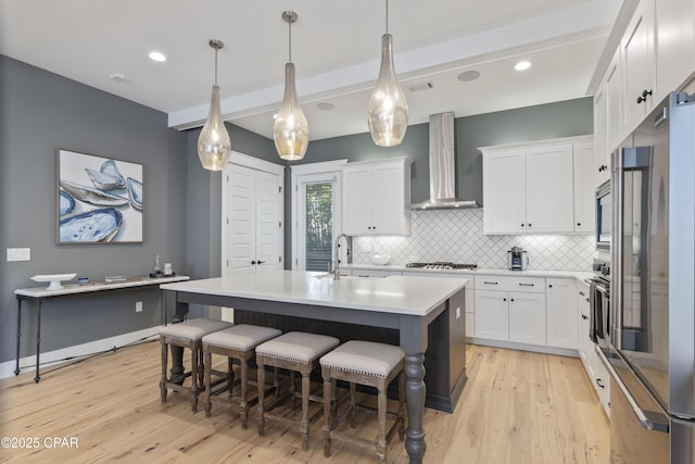 kitchen featuring white cabinetry, sink, stainless steel appliances, and wall chimney exhaust hood