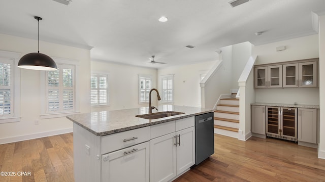 kitchen featuring sink, dishwasher, wine cooler, light stone counters, and decorative light fixtures