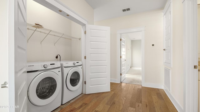 laundry room with light hardwood / wood-style floors and washer and dryer