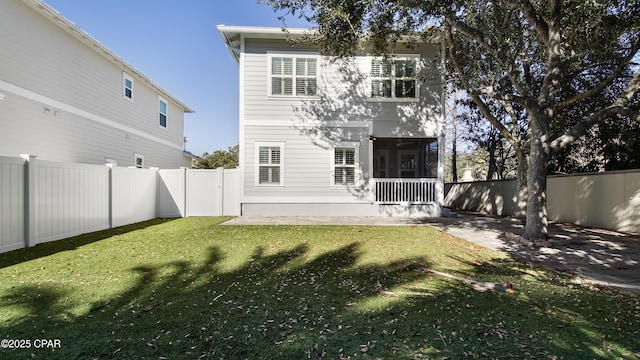 rear view of house featuring a yard and a sunroom