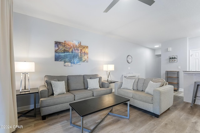 living room featuring a fireplace, baseboards, a ceiling fan, and wood finished floors