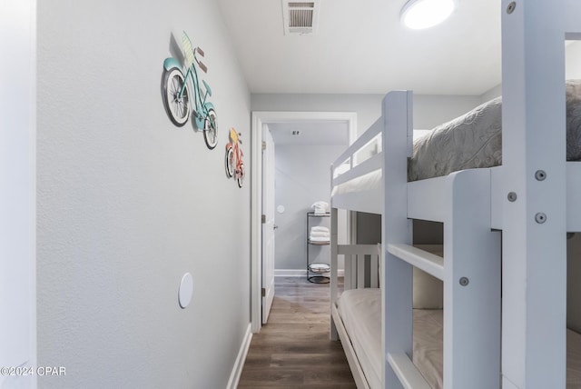 corridor featuring visible vents, baseboards, and wood finished floors