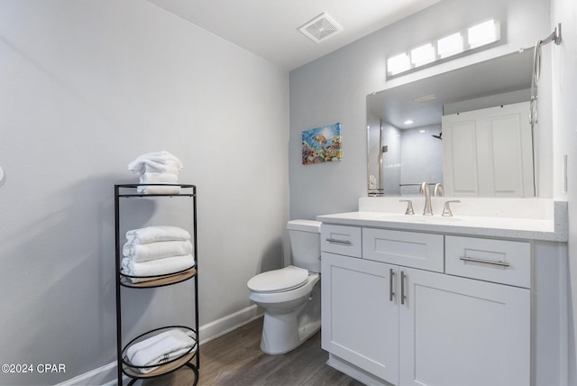 bathroom with visible vents, toilet, wood finished floors, baseboards, and vanity