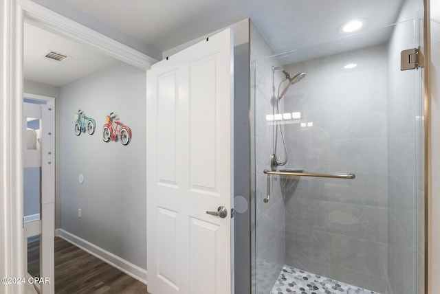 bathroom with wood finished floors, visible vents, baseboards, and a stall shower