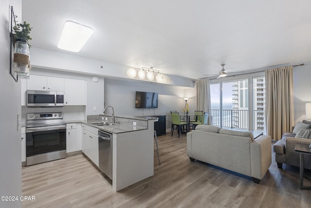 kitchen with sink, appliances with stainless steel finishes, kitchen peninsula, hardwood / wood-style floors, and white cabinets