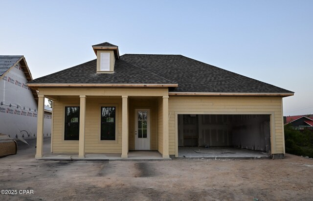 view of front of property with covered porch, a shingled roof, and a garage