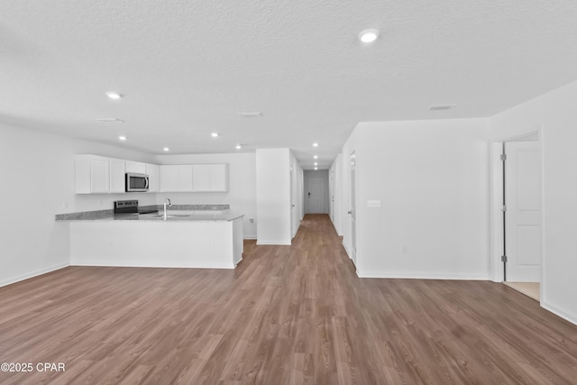 kitchen with white cabinetry, light hardwood / wood-style floors, stainless steel appliances, and kitchen peninsula