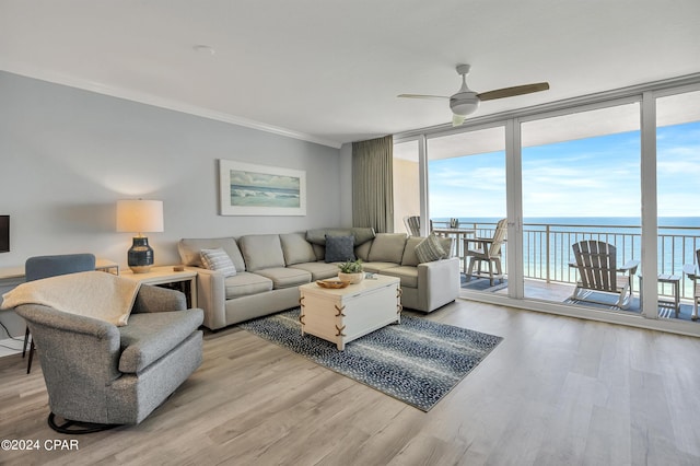 living room with floor to ceiling windows, light hardwood / wood-style flooring, ornamental molding, and a water view