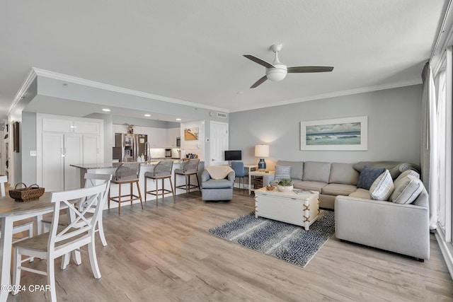 living room featuring crown molding, a ceiling fan, and light wood finished floors