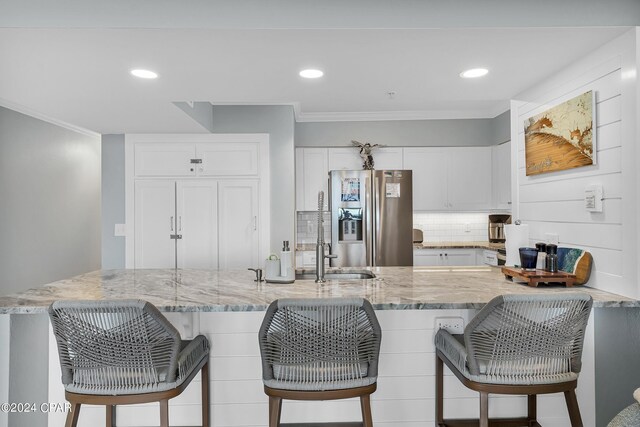 kitchen featuring light stone countertops, a kitchen breakfast bar, white cabinetry, and appliances with stainless steel finishes