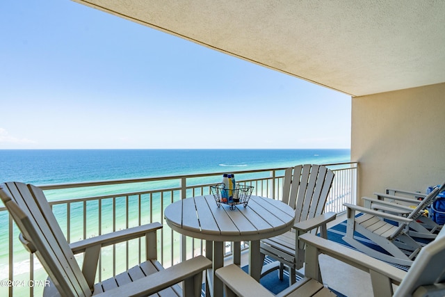 balcony with outdoor dining area and a water view