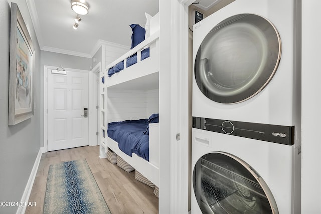 bedroom with stacked washer / dryer, light hardwood / wood-style floors, and ornamental molding