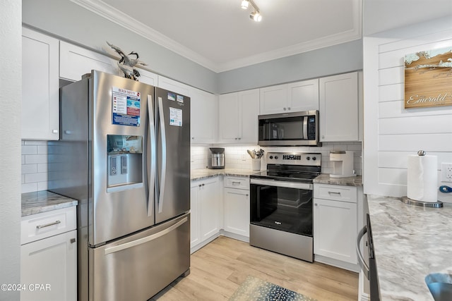 kitchen featuring light hardwood / wood-style flooring, appliances with stainless steel finishes, backsplash, white cabinetry, and light stone countertops