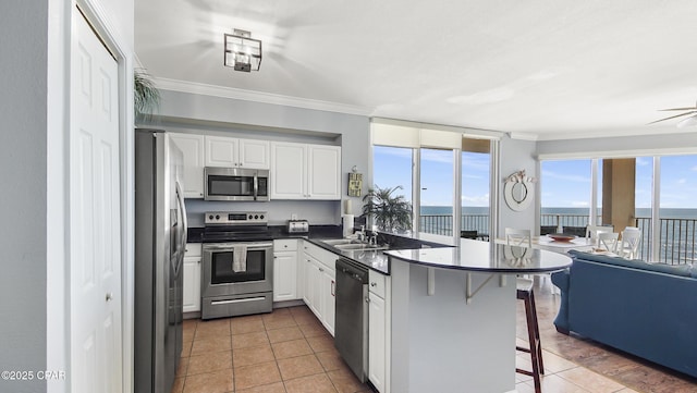 kitchen featuring stainless steel appliances, kitchen peninsula, a breakfast bar area, and white cabinets