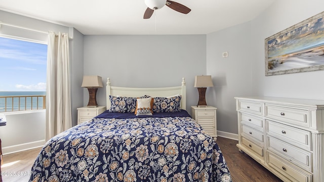 bedroom featuring dark hardwood / wood-style flooring, a water view, and ceiling fan