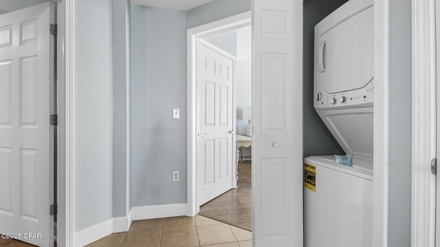 washroom with light tile patterned flooring and stacked washer / drying machine