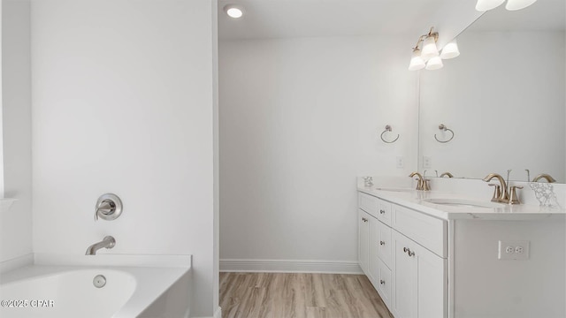 full bathroom with double vanity, a tub, a sink, and wood finished floors