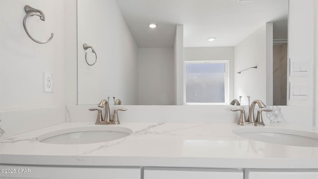 bathroom featuring double vanity, a sink, and recessed lighting