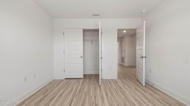 unfurnished bedroom with light wood-style floors, baseboards, visible vents, and a closet