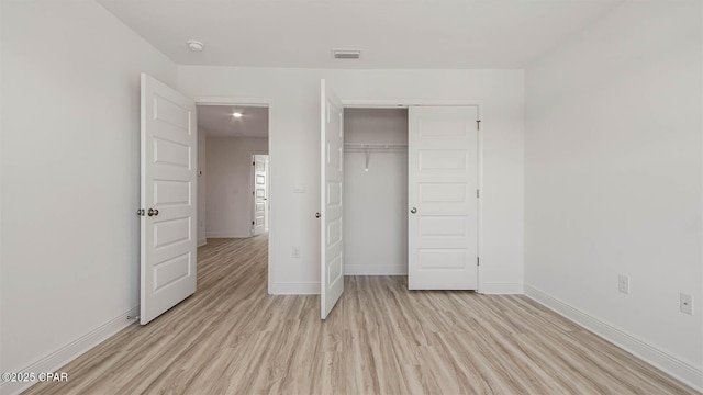 unfurnished bedroom featuring visible vents, a closet, light wood-style flooring, and baseboards