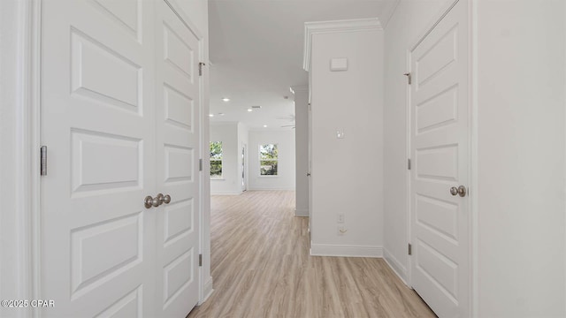 hall with light wood finished floors, baseboards, and ornamental molding