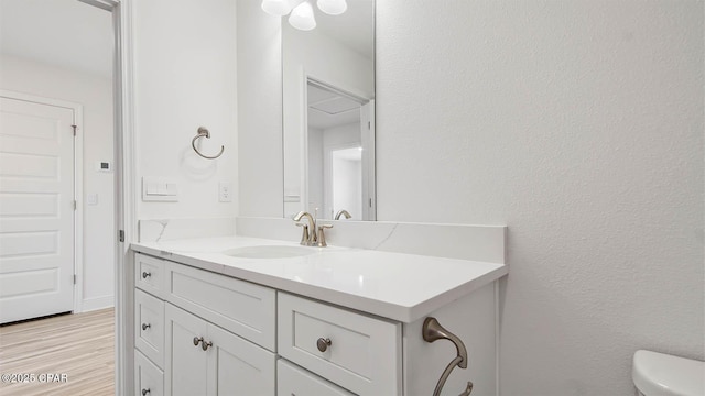 bathroom featuring toilet, wood finished floors, and vanity