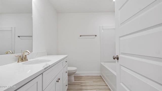 bathroom with toilet, wood finished floors, vanity, and baseboards