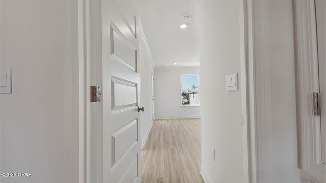 hallway with light wood-type flooring, crown molding, and baseboards