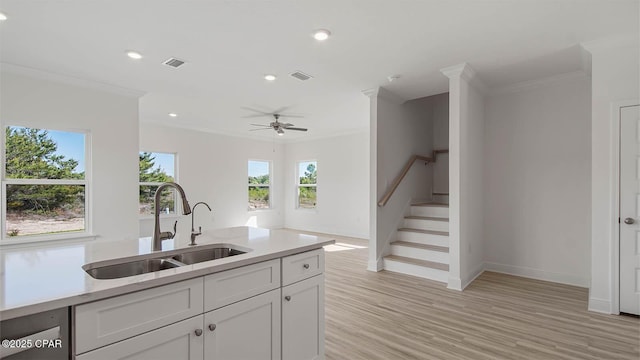 kitchen with crown molding, light countertops, visible vents, and a sink