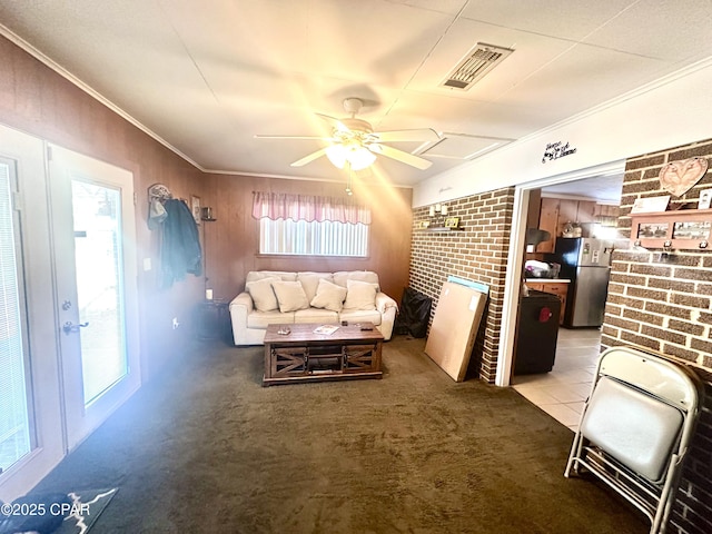 living room with crown molding, ceiling fan, brick wall, and a brick fireplace