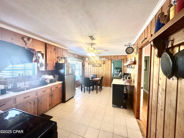 kitchen with wooden walls, black electric range oven, sink, stainless steel fridge, and crown molding