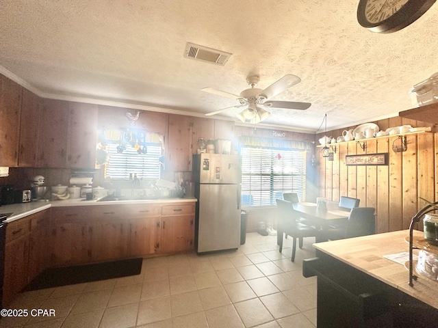 kitchen with ornamental molding, fridge, and wooden walls