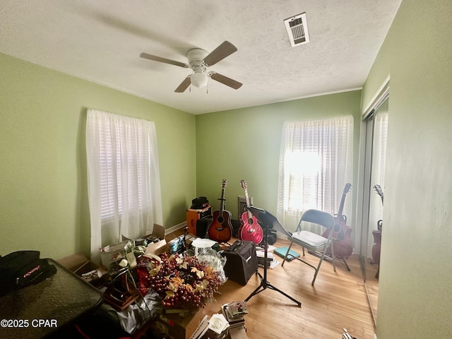 misc room with ceiling fan, light hardwood / wood-style floors, and a textured ceiling