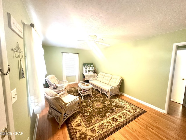 living area with hardwood / wood-style floors, a textured ceiling, and ceiling fan